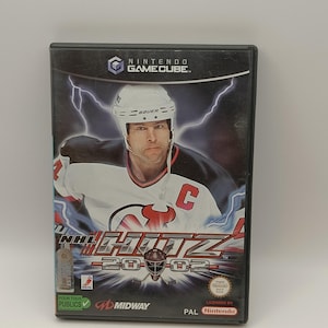 Puede incluir: Caja de videojuego de Nintendo GameCube para NHL Hitz 20-02. La portada presenta a un jugador de hockey sobre un fondo de rayos. El juego tiene licencia de Nintendo.