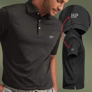 May include: Black polo shirt with a collared neckline and three buttons. The shirt features the embroidered initials "BP" on the chest and sleeve. A side view of the shirt is also shown, highlighting the details of the design.