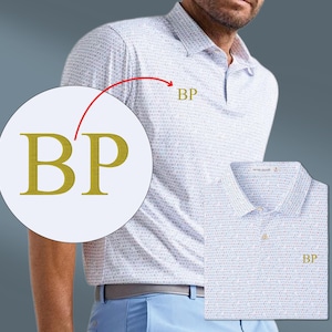 May include: A white polo shirt with a subtle pattern and the embroidered letters "BP" in gold. The shirt has a classic collar and buttoned placket. The model is wearing light blue pants.