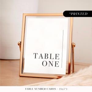Minimal modern table numbers, bold typographic personalised printed table names, simple monochrome wedding reception table cards