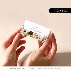 Tarjetas de lugar para bodas de otoño en color burdeos, tarjetas con nombres de invitados impresos con flores otoñales, tarjetas de lugar planas o plegadas con motivos florales y helechos.