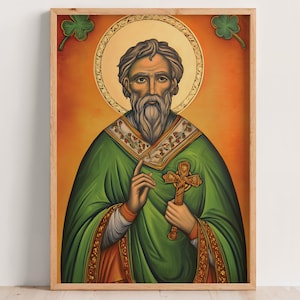 Op de afbeelding: Ingelijste prent van een religieuze figuur in een groene jurk, met een gouden kruis en een halo. Het kunstwerk heeft warme oranje- en goudtinten, en klavers bevinden zich in de hoeken.