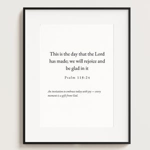 Puede incluir: Impresión enmarcada con fondo blanco y texto negro. El texto dice: "Este es el día que el Señor ha hecho; regocijémonos y alegrémonos en él." Salmo 118:24. Debajo, dice: "Una invitación a abrazar hoy con alegría - cada momento es un regalo de Dios."
