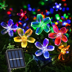 May include: Solar-powered string lights with flower-shaped LED lights in various colours, including blue, green, red, and yellow. The lights are arranged on a dark background with a solar panel visible.