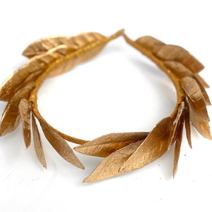 May include: A gold laurel wreath headband with a circular shape and multiple leaves.