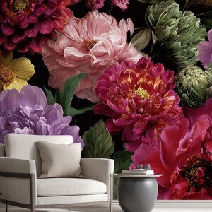 Può includere: Una vivace carta da parati floreale con grandi fiori colorati nei toni del rosa, rosso, viola e giallo su uno sfondo nero. Una poltrona bianca e un tavolino sono in primo piano, creando un design d'interni accogliente.