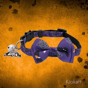 May include: A purple Halloween-themed cat collar with a matching bow tie. The collar features a black buckle and a charm with a bat and bell. The bow tie has a spiderweb and bat design. The brand name "Kiokatt" is visible.