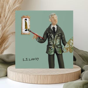 May include: A square art print depicting a claymation figure of a painter with a paintbrush and palette. The figure wears a dark suit with paint splatters. A framed painting hangs on the wall. The text "L.S. LOWRY" is at the bottom of the print.