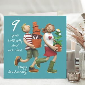 May include: A teal anniversary card with a cartoon illustration of a couple carrying plant pots. The card reads "9 years & still potty about each other! Happy Anniversary!" in white script. The couple is depicted in a whimsical style.