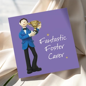 May include: A purple greeting card with the text "Fantastic Foster Carer" in white script. The card features a figurine of a person in a blue jacket and black trousers holding a gold trophy. The trophy has the words "Top Foster".