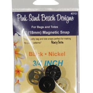 May include: A clear plastic package containing magnetic snaps for bags and totes. The package features the text "Pink Sand Beach Designs" and "(18mm) Magnetic Snap". The snaps are black and nickel, measuring 3/4 inch.