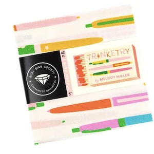 Peut inclure: Un paquet de charms en tissu avec un fond blanc et des illustrations de stylos colorés. Le paquet comprend une étiquette noire avec le texte "Ruby Star Society" et une petite carte avec le mot "Trinketry" et "by Melody Miller".