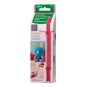 May include: A pink plastic stuffing tool by Clover, model 3222, packaged in a tall rectangular box. The packaging features green and white branding, text in multiple languages, and illustrations showing a blue crocheted toy being filled with stuffing.