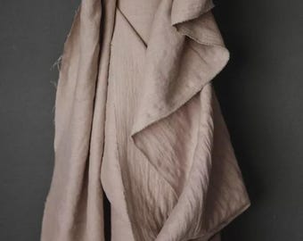 May include: A draped, beige fabric against a dark gray background. The fabric has a soft, textured appearance with visible folds and edges. The neutral color and simple design suggest a focus on natural materials.
