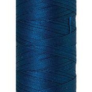 May include: A spool of dark teal silk-finish thread. The spool has a light pink top and bottom with the brand name "Mettler" printed on the top. The thread is wound tightly around the spool, and the label indicates 164 yards of thread.