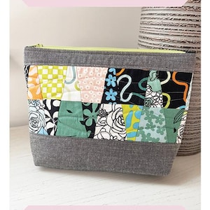 May include: A rectangular patchwork pouch with a gray base and top, and a colorful patchwork design in the middle. The pouch has a yellow zipper and the text "Patchwork Slice Pouch". The pouch measures 8" x 10".