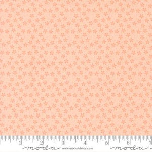 May include: Peach-colored fabric with a repeating floral pattern. The flowers are small and evenly spaced across the surface. A ruler is at the bottom, marked in inches.