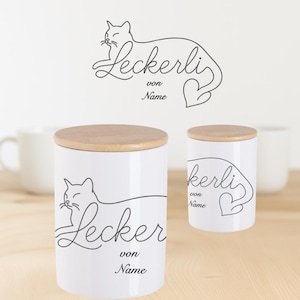 Könnte beinhalten: Weiße Keramik-Leckerli-Gläser für Haustiere mit Holzdeckeln. Die Gläser zeigen eine schwarze Strichzeichnung einer Katze und das Wort "Leckerli" mit "von Name" darunter. Ein ähnliches Design befindet sich an der Wand.
