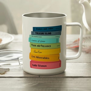 May include: White coffee mug featuring a stack of colorful book spines with titles like "Romeo and Juliet" and "Pride and Prejudice." The mug has a silver rim and a white handle. The mug is on a wooden table.