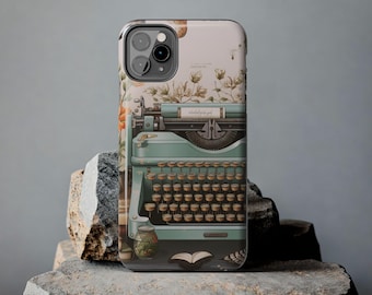 May include: A teal blue vintage typewriter with a floral design on a white background. The typewriter has a black keyboard and a white paper holder. The floral design includes white flowers and green leaves.
