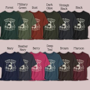 May include: A collection of t-shirts in various colors, including forest green, navy, and maroon. Each shirt features a graphic of a frog reading a book under a tree, with the text "Escaping Reality...one book at a time."