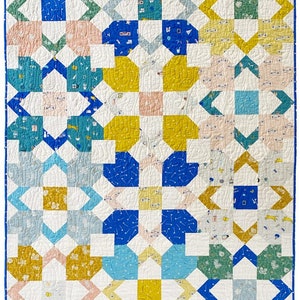 May include: A quilt with a geometric pattern in shades of blue, yellow, green, and pink. The quilt is made up of squares and rectangles, and the pattern is repeated throughout the quilt.