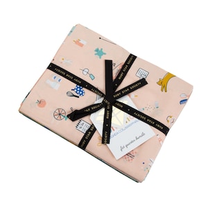 May include: A bundle of pink fabric with a white and blue patterned design. The fabric is tied with a black ribbon and has the text "Ruby Star Society" printed on it. The fabric is labelled as a "fat quarter bundle".