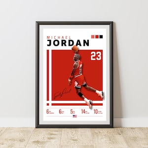 Könnte beinhalten: Gerahmtes Poster mit Michael Jordan in einem rot-weißen Chicago Bulls-Trikot, in der Luft mit einem Basketball. Das Poster enthält den Namen "Michael Jordan", die Nummer "23" und seine Unterschrift. Das Poster ist in einem schwarzen Rahmen.
