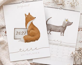 Peut inclure: Un calendrier mural 2027 intitulé "tiere WANDPLANER" par fridafriederike. La couverture présente une illustration à l'aquarelle d'un renard brun tenant un panneau avec l'année 2027. Une page ouverte montre un teckel gris avec une fleur blanche.
