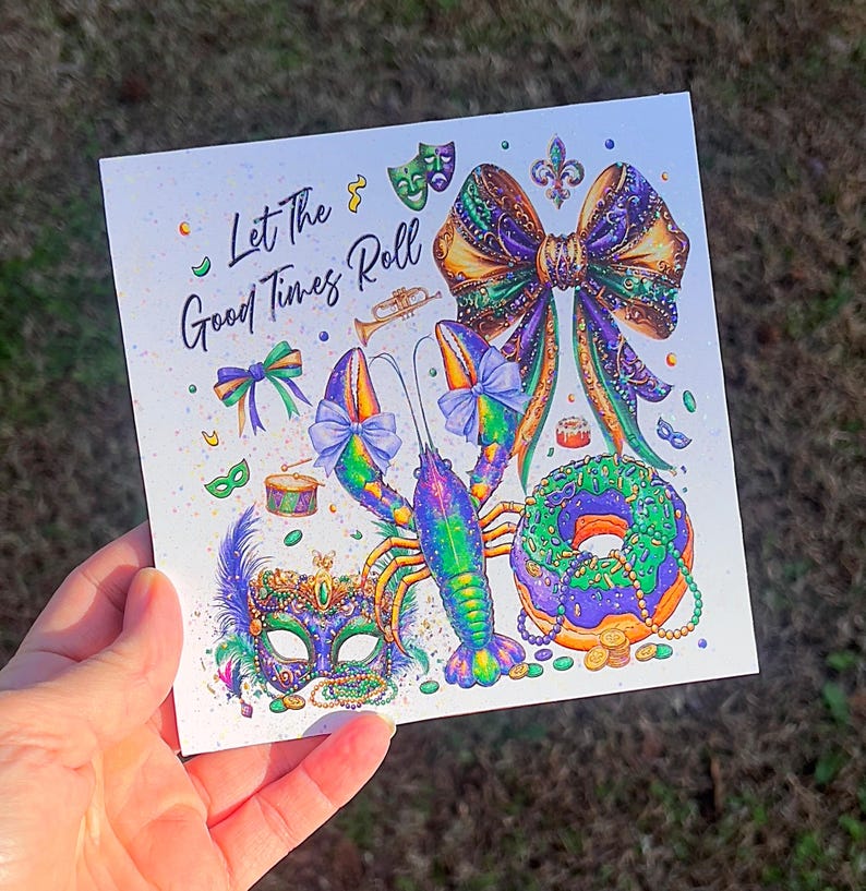 Pode incluir: Cart&atilde;o quadrado com uma ilustra&ccedil;&atilde;o colorida apresentando uma lagosta, uma m&aacute;scara, um la&ccedil;o e uma rosquinha, com o texto "Let The Good Times Roll". O design incorpora elementos roxos, verdes, dourados e azuis, evocando um tema festivo.