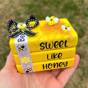 May include: A stack of three yellow painted wooden blocks with the words "Bee Sweet Like Honey" and bee and honeycomb designs. The top block has a 3D bee and honeycomb design.