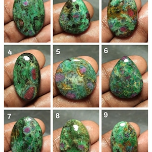 May include: Nine polished gemstones in shades of green, red, and brown. Each stone displays a unique pattern and shape, with variations in colour distribution. The gemstones are oval, teardrop, and round, and are displayed against a neutral background.