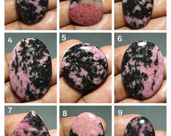 Puede incluir: Nueve piedras preciosas de rodocrosita pulidas con patrones rosas y negros. Las piedras tienen varias formas, incluyendo ovaladas, de lágrima y redondas. Las piedras preciosas se muestran sobre un fondo neutro.