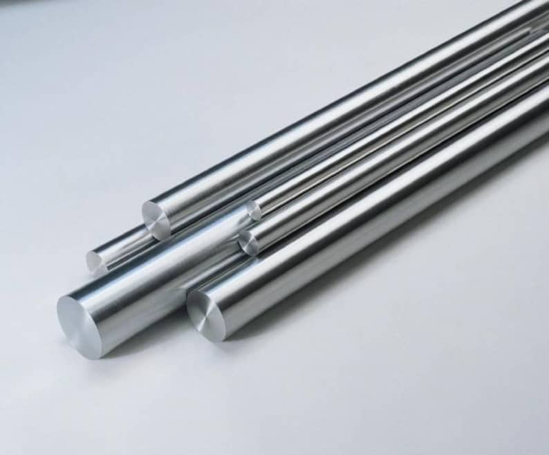 May include: A collection of several shiny, cylindrical metal rods of varying diameters. The rods are arranged diagonally across the frame, with their ends visible, reflecting light. The overall appearance is clean and industrial.