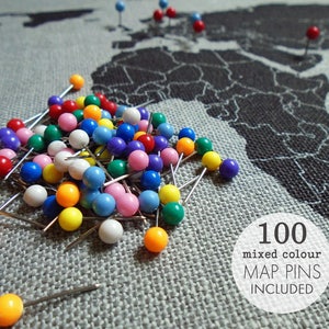 May include: A pile of 100 mixed color map pins on a gray fabric background with a world map printed on it. The text "100 mixed colour MAP PINS INCLUDED" is printed on a white circle.