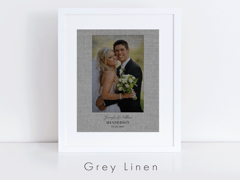 May include: A framed wedding photograph printed on a grey linen canvas. The photo shows a bride and groom smiling at the camera. The text below the photo reads "Jennifer & William Henderson 07.10.2017".
