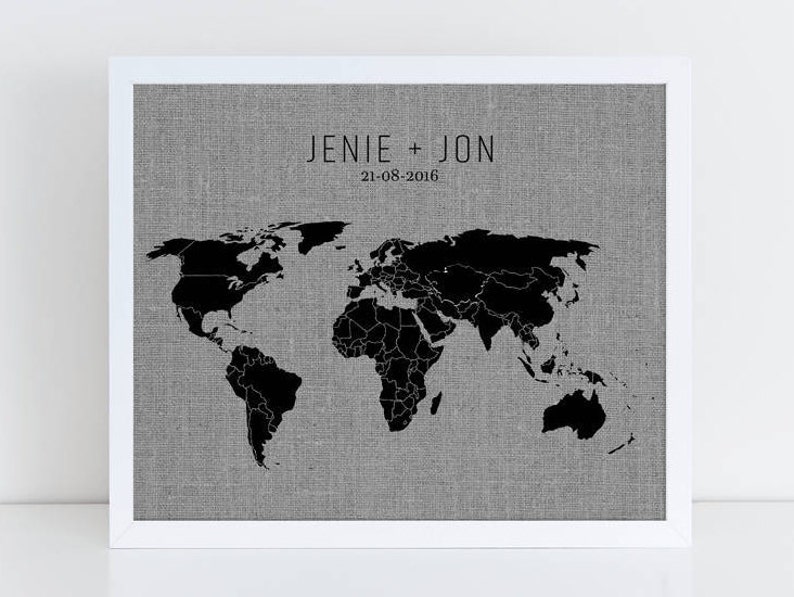 May include: A black and white world map print on a gray linen background with the text "JENIE + JON 21-08-2016" above the map.