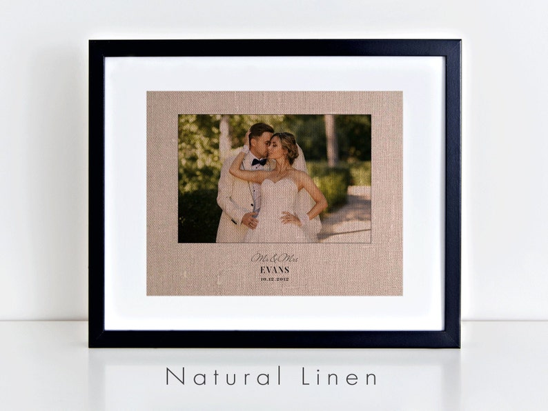 May include: A framed photograph on natural linen with a black frame. The photograph shows a couple kissing. The text below the photograph reads "Mr. & Mrs. Evans 10.01.2012".