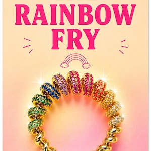 Puede incluir: Un brazalete dorado con diseño en espiral, adornado con gemas coloridas en un patrón de arcoíris. La imagen incluye el texto "THE RAINBOW FRY" en rosa, con un gráfico de arcoíris.
