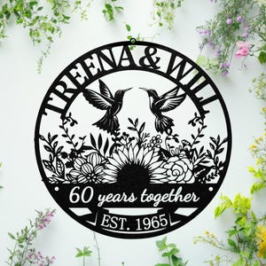 May include: Black metal wall art featuring the names "TREENA & WILL" and two hummingbirds facing each other. The design includes floral elements and the text "60 years together" and "EST. 1965" in a circular shape.