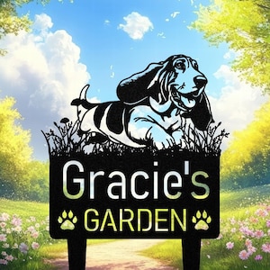 May include: Black metal garden sign with a Basset Hound silhouette above the text "Gracie's GARDEN". The sign includes paw prints and is designed for outdoor use. The background shows a blue sky and a green garden.