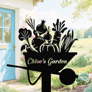 May include: Black metal garden sign featuring a wheelbarrow silhouette filled with vegetables. The sign includes the text "Chloe's Garden" in a decorative font, perfect for outdoor decor.