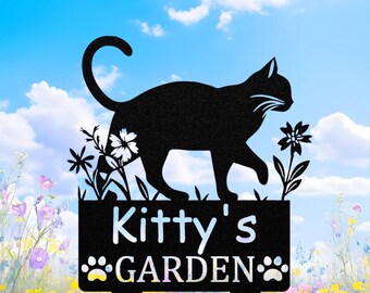 May include: Black metal garden stake featuring a silhouette of a cat walking above a sign that reads "Kitty's GARDEN" in white. The sign includes paw prints and is decorated with floral accents. The background shows a blue sky with clouds and a flower garden.