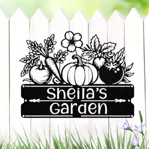May include: Black metal garden sign with the text "Sheila's Garden" and a decorative arrangement of vegetables and a flower. The design includes a tomato, carrot, pumpkin, and leaves, perfect for outdoor decor.