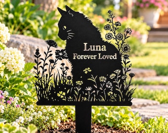 Op de afbeelding: Een zwarte metalen tuinpaal met een silhouet van een kat die tussen wilde bloemen zit. De tekst "Luna" en "Forever Loved" is uit het midden van het kattenlichaam gesneden. Het ontwerp bevat diverse bloemstengels en bladeren.