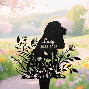 Könnte beinhalten: Schwarzer Metall-Gartenstecker mit einer Hundesilhouette, floralen und Blattausschnitten. Der Name "Lucy" und die Jahre "2022-2025" sind auf dem Körper des Hundes eingraviert. Ein Schmetterling ist ebenfalls enthalten.