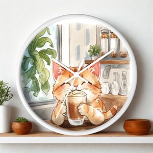 Op de afbeelding: Een ronde wandklok met een witte rand voorzien van een aquarelillustratie van een oranje cyperse kat die een glazen mok koffie met slagroom vasthoudt. De achtergrond toont een keuken met een raam, een groene plant en glazen potten.