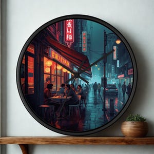 May include: A round wall clock with a black frame featuring a printed scene of a rainy city street at night. The image depicts people sitting at tables outside a restaurant with glowing red neon signs, streetlights, and a car on a wet road.