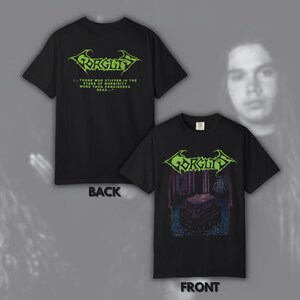 Puede incluir: Camisetas negras con el nombre de la banda "Gorguts" en verde, con un gráfico en la parte delantera y texto en la parte trasera. El gráfico frontal representa una escena oscura y gótica. La parte trasera de la camiseta tiene el logotipo y el texto de la banda.