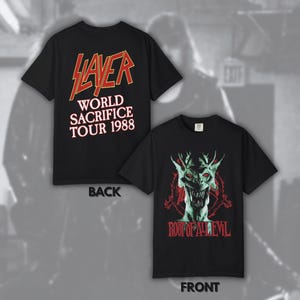 May include: A black short-sleeved t-shirt featuring a Slayer World Sacrifice Tour 1988 graphic on the back in red and white text. The front displays a green demonic creature graphic with red eyes above the red text Root of All Evil.